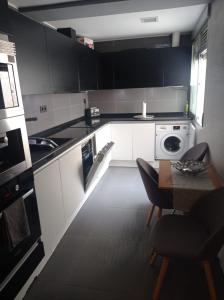 una cocina con armarios en blanco y negro y una mesa en Elche piso entero 3 dormitorios dobles en Elche