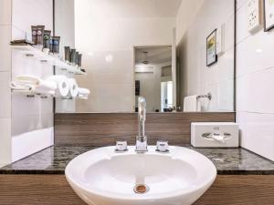 un lavabo blanc dans une salle de bain avec un miroir dans l'établissement Novotel Darwin CBD, à Darwin