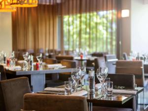 a restaurant with tables and chairs with wine glasses at Novotel Canberra in Canberra