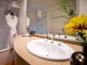 a bathroom with a sink and a large mirror at Novotel Canberra in Canberra