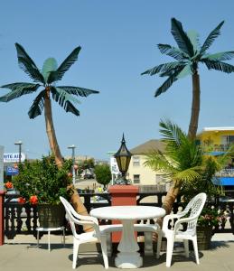 une table et des chaises sur une terrasse avec des palmiers dans l'établissement Casa Del Sol Motel, à Wildwood