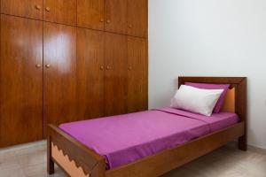 Green Sunshine في ثيولوغيس: غرفة نوم مع سرير مع أوراق أرجوانية ودواليب خشبية