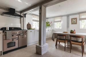 a kitchen with a stove and a table with chairs at Cosy Cottage with Beautiful Garden, HotTub & Sauna in Marden