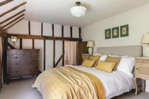 a bedroom with a large bed and a wooden dresser at Cosy Cottage with Beautiful Garden, HotTub & Sauna in Marden