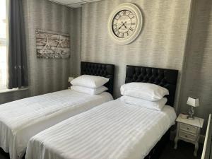 two beds in a bedroom with a clock on the wall at Sea-Renity - Self Catering Holiday Let in Douglas