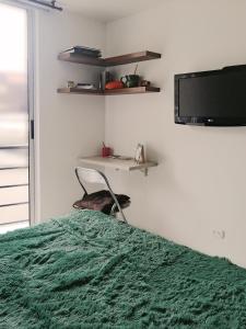 - une chambre avec un lit vert et une télévision dans l'établissement Cálido apartaestudio en La Castellana, à Armenia