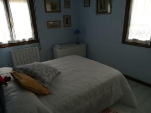 a white bed in a bedroom with two windows at APARTAMENTO PLAYA DE USIL in Mogro