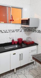 eine Küche mit einer Spüle und einer Mikrowelle in der Unterkunft Apto Aeroporto Macae in Macaé