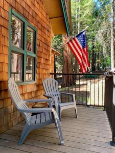 Dos sillas y una mesa en un porche con bandera americana en The Cedar Loft - Pet and Family Friendly - BBQ/Pool/Fire Pit, en Camp Connell