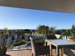 a patio with a table and chairs on a balcony at Ohope Beach Resort in Ohope Beach