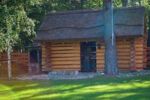a log cabin with a door and a tree at SASKI ZAKĄTEK, WAKACJE W BAJKOWYM DOMKU!!! MAZURY, SAUNA, JEZiORO, POMOST, in Sasek Mały