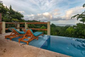 two chairs sitting next to a swimming pool at Casa Chameleon Hotel Mal Pais - Adults Only in Santa Teresa Beach