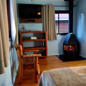 um quarto com uma cadeira e um fogão a lenha em Pousada Cabanas Xokleng em Urubici