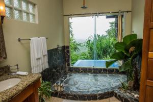 a bathroom with a tub and a shower with a window at Casa Chameleon Hotel Mal Pais - Adults Only in Santa Teresa Beach