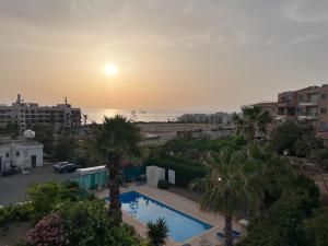 vistas a una piscina con palmeras y a la puesta de sol en Daimond Complex Sea View Apartment en Pafos