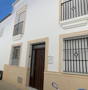 una casa bianca con una porta marrone e due finestre di Casa con chimenea y terraza 6 PERSONAS a Olvera