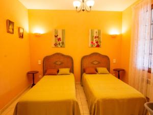 two beds in a room with yellow walls at Maison confortable près de Périgueux avec cheminée, jardin et animaux admis - FR-1-616-10 in Bassillac