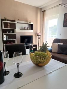 una sala de estar con una mesa con un tazón de frutas y copas de vino en Apartment Žunabović, en Trogir