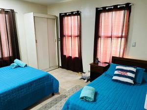 a bedroom with two beds with blue sheets and windows at Apartamento The Garden in Liberia