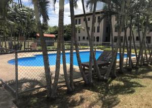 a fence with a bench next to a pool with palm trees at Apartamento The Garden in Liberia