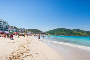 a group of people walking on a beach at Mediterrane Hotel by Castelo Itaipava in Arraial do Cabo