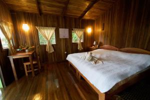Schlafzimmer mit einem Bett mit weißer Bettwäsche und Holzwänden in der Unterkunft El Mirador Glamping & Apartments & Woodhouse & Swimingpool in Miramar