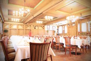 een eetkamer met witte tafels en stoelen en kroonluchters bij Schmiede Hotel in Schoenberg
