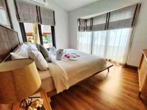 a bedroom with a large white bed with windows at Supalai Scenic Bay Resort And Spa, SHA Extra Plus in Por Bay