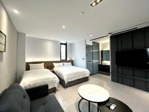 1 dormitorio con 2 camas, sofá y TV en House Apartment en Magong