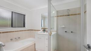 a bathroom with a shower and a tub and a sink at Hoddle Lane in Robertson