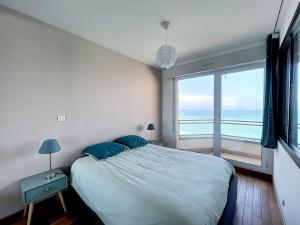 ein Schlafzimmer mit einem großen Bett und einem großen Fenster in der Unterkunft Charmant T2 en front de mer, 4 pers., ascenseur, garage, Wi-Fi - FR-1-361-383 in Granville
