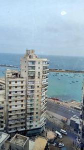 - un grand bâtiment au bord de l'océan avec des bateaux dans l'eau dans l'établissement شقه فى ميامى بالاسكندريه مطله على البحر, à Alexandrie