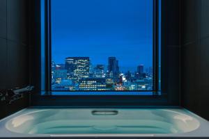a bath tub with a window with a city view at The Royal Park Hotel Iconic Osaka Midosuji in Osaka