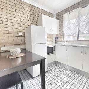 a kitchen with a table and a white refrigerator at Raceview Motor Inn in Toowoomba