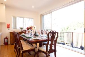een eetkamer met een tafel en stoelen en een balkon bij The roses house - Cozy and Modern house in Katoomba in Katoomba