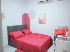 a bedroom with a bed with a red comforter at Yoni Homestay in Kampung Raja