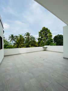 a large patio with a white wall and palm trees at Happy Homes in Kiribathgoda