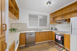 a kitchen with wooden cabinets and stainless steel appliances at Regency Court 4 in The Entrance