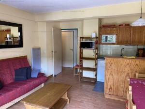 a living room with a red couch and a kitchen at Appartement Les Angles, 3 pièces, 6 personnes - FR-1-295-183 in Les Angles