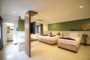 Una sala de estar con dos camas y un televisor. en Kaya Place, en Bangkok