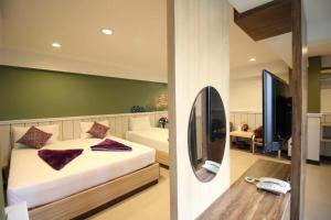 1 dormitorio con 1 cama, TV y espejo en Kaya Place, en Bangkok
