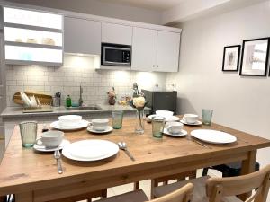a wooden table in a kitchen with white plates and silverware at CRIB 227: Modern Fresh Vibe Condo in Olongapo