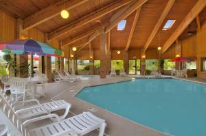 a large swimming pool with chairs and a table and umbrella at Baymont by Wyndham Muskegon in Muskegon