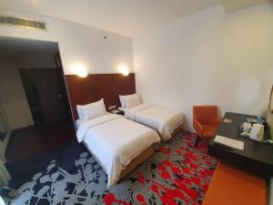 a hotel room with two beds and a desk and a desk at Liberty Hotel Thamrin Jakarta in Jakarta