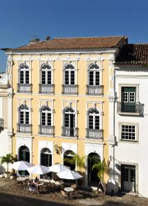 um edifício amarelo com mesas e guarda-chuvas à sua frente em Hotel Villa Bahia em Salvador