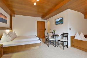 a bedroom with a bed and a table and chairs at Landhaus zum Griena in Mayrhofen