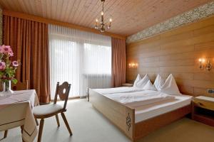 a bedroom with a bed and a table and a chair at Landhaus zum Griena in Mayrhofen