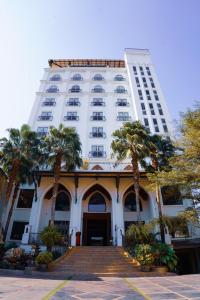 a tall white building with palm trees in front of it at Capitol Residence in Vientiane