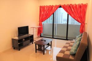 ein Wohnzimmer mit einem Sofa, einem TV und einem Fenster in der Unterkunft Suasana Suites D'Homestay2 JB Town in Johor Bahru
