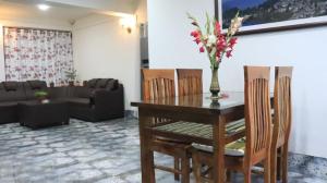 a living room with a table with a vase with flowers on it at RHODODENDRON stay in Darjeeling